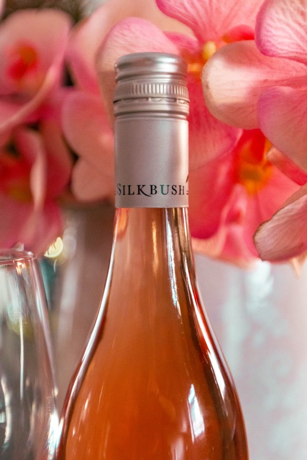 Close-up of a Silkbush wine bottle neck styled with pink orchid flowers
